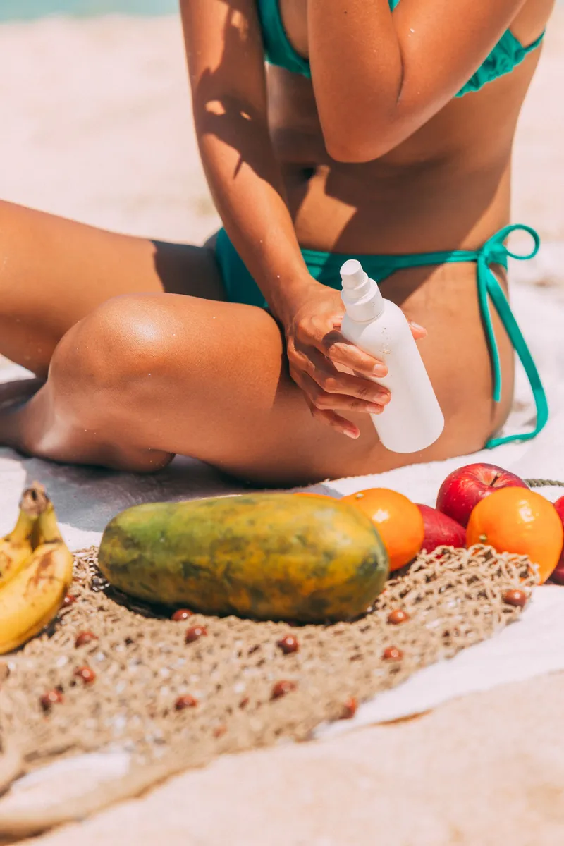 Persona aplicándose crema solar en la piel en la playa