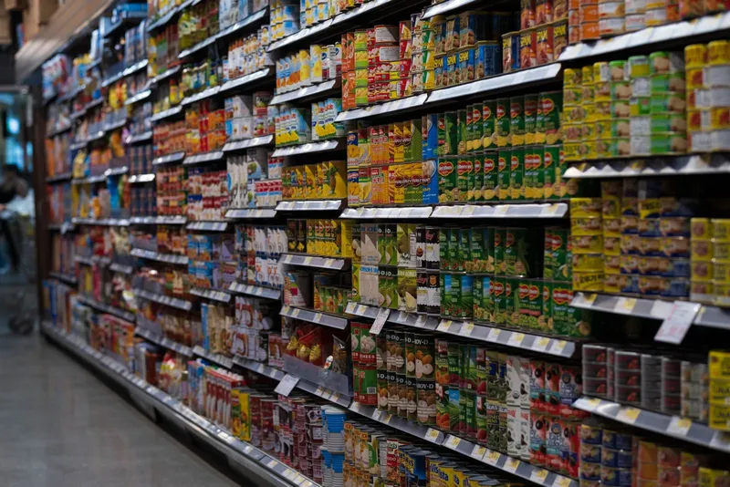 Pasillo de supermercado con estanterías llenas de latas de conserva